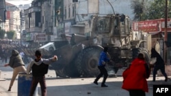 Des Palestiniens lancent des pierres sur un bulldozer de l'armée israélienne, lors d'affrontements dans la ville de Jénine, en Cisjordanie occupée, le 26 janvier 2023.