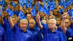 លោក Ahmad Zahid Hamidi ប្រធានសម្ពន្ធភាពចម្រុះនៃគណបក្ស UMNO និងគណបក្ស Barisan National (ឆ្វេង) និងលោក Ismail Sabri Yaakob នាយករដ្ឋមន្ត្រីនៃរដ្ឋាភិបាលចាំផ្ទះ (ស្តាំ) បក់ទង់ជាតិម៉ាឡេស៊ី នៅទីក្រុងគូឡាឡាំពួ កាលពីថ្ងៃទី១ ខែវិច្ឆិកា ឆ្នាំ២០២២។