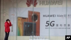 疫情期間一名婦女站在位於北京的華為手機5G廣告旁。（2020年3月8日）
