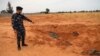 Un membre des forces de sécurité fidèles au GNA pointe vers une fosse commune à Tarhouna, en Libye, le 11 juin 2020.