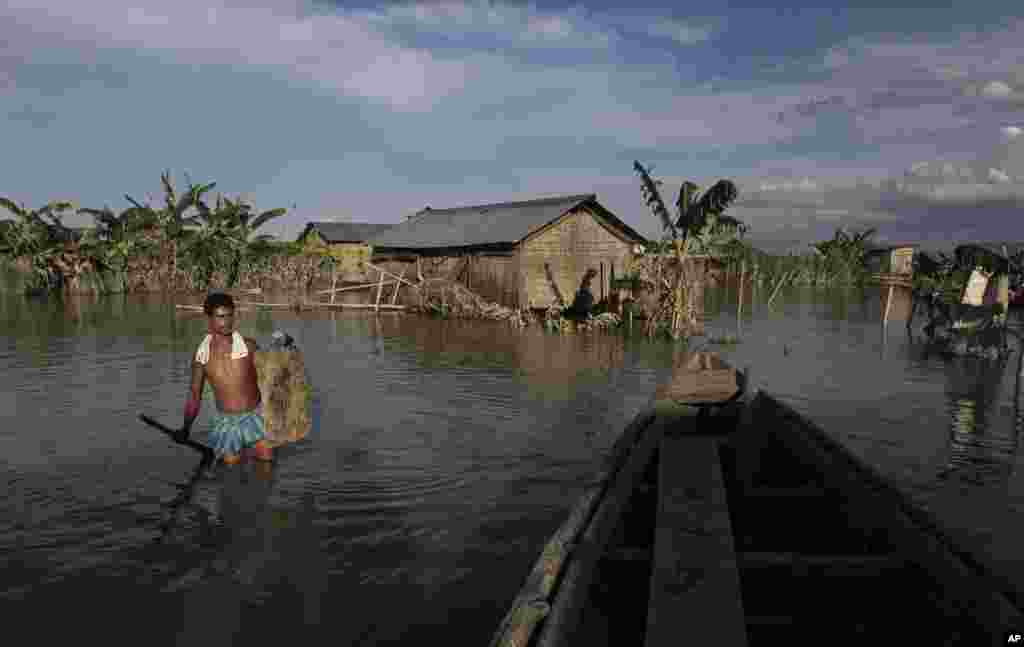 An Indian villager wades through flood waters at Gagalmari village in Assam state, India, July 2, 2012.