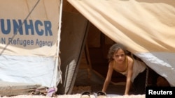 FILE - A Syrian refugee girl looks out from a tent amidst dust at Al Zaatri refugee camp in the Jordanian city of Mafraq, near the border with Syria, Aug. 13, 2012.