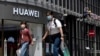 Residents wearing face masks to protect against the coronavirus walk past a Huawei retail store in Beijing on Monday, May 18, 2020. China's commerce ministry says it will take "all necessary measures" in response to new U.S. restrictions on Chinese…