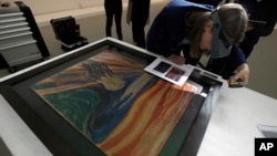 Un conservateur examine un tableau lors d’une exposition à la Fondation Vuitton, au musée d’Oslo, à Paris, France, 6 juillet 2015.