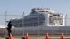 A photographer takes photos near the quarantined Diamond Princess cruise ship anchored at a port in Yokohama, near Tokyo, Friday, Feb. 21, 2020. Passengers tested negative for COVID-19 started disembarking since Wednesday. (AP Photo/Eugene Hoshiko)