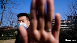 中國安全人員阻擋新聞攝影師拍攝世界衛生組織一個專家組在武漢的行踪（路透社2021年2月6日）