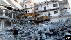 Des ouvriers enlèvent les décombres d'un bâtiment détruit par une frappe aérienne israélienne, dans la ville de Gaza, le mardi 15 juin 2021. Le bâtiment a été endommagé le mois dernier lors d'une guerre de 11 jours entre Israël et le groupe militant du Hamas qui dirige Gaza.
