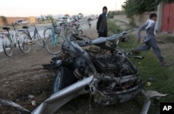 FILE - Afghans gather at the site of a suicide car bomb attack in the Qarabagh district of Kabul, Afghanistan, Sept. 12, 2015. The attacker targeted an Afghan lawmaker’s son, who survived. On Sept. 23, 2017, officials confirmed that scores of Taliban fighters attacked security outposts in the district, killing five policemen.