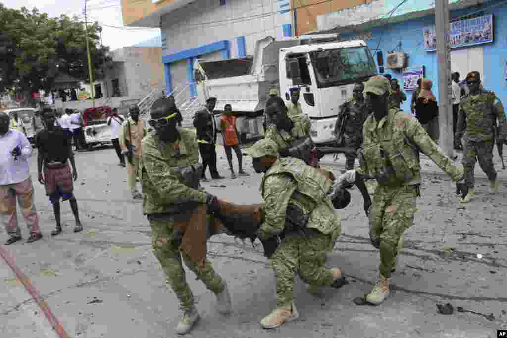 Les soldats somaliens transportent un cadavre qui a été tué dans l'attaque à Mogadiscio, en Somalie, le 30 juillet 2017.