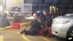 FILE - Image made from video shows Alton Sterling being restrained by two Baton Rouge police officers, one holding a gun, outside a convenience store in Baton Rouge, Louisiana, July 5, 2016, before one of the officers shot and killed Sterling, a black man who had been selling CDs outside the store, while he was on the ground.