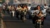 A local woman, foreground right, drives her motorbike as she carries her baby and a dog on a busy street in Phnom Penh, Cambodia, Tuesday, Feb. 18, 2014. (AP Photo/Heng Sinith)