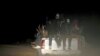 FILE - Migrants sit at the back of a truck as it is driven through a dust road at night in the desert town of Agadez, Niger, May 25, 2015.