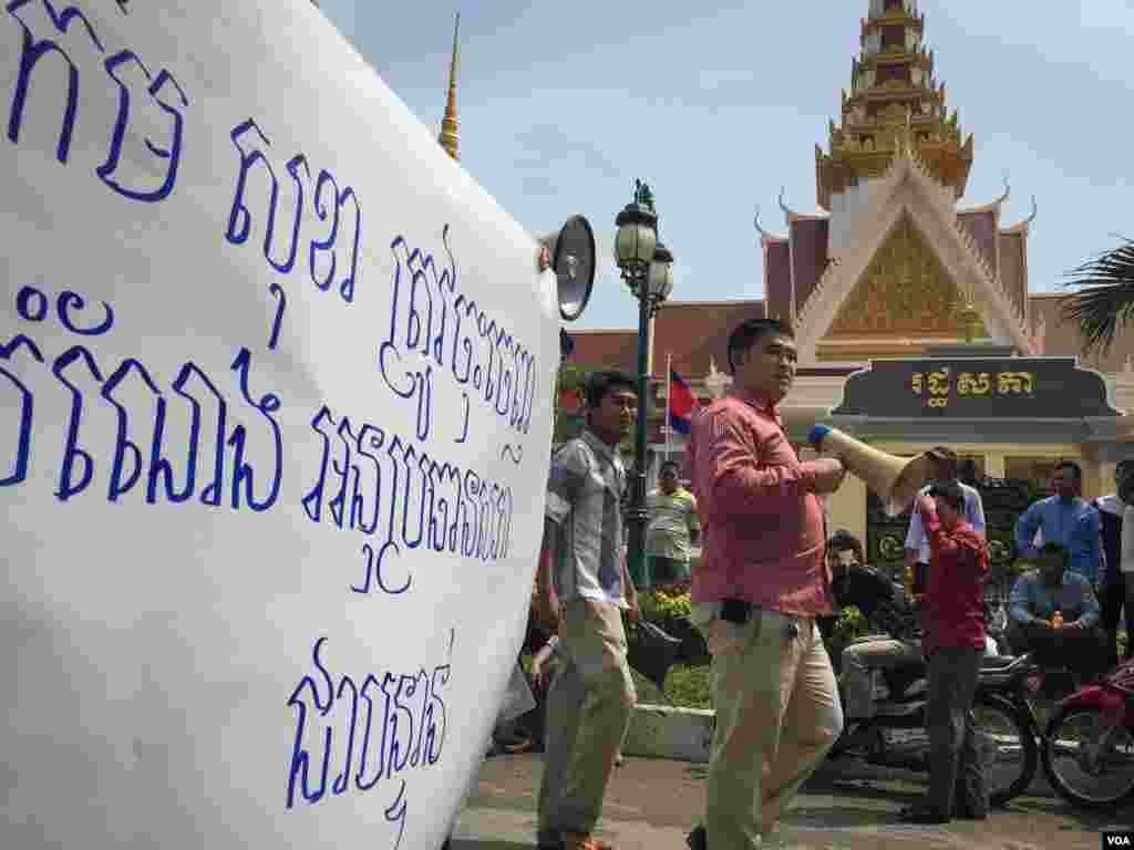 ផ្ទាំងបដាពាក្យស្លោកទាមទារឲ្យលោក កឹម សុខា អនុប្រធានទី១នៃរដ្ឋសភាជាតិនិងជាអនុប្រធានគណបក្សសង្គ្រោះជាតិ ចុះចេញពីតំណែង ត្រូវបានលើកឡើងដោយក្រុមអ្នកតវ៉ាខណៈពេលដែលពួកគេបានប្រមូលផ្តុំគ្នានៅមុខរដ្ឋសភាជាតិ កាលពីព្រឹកថ្ងៃច័ន្ទ ទី២៦ ខែតុលា ឆ្នាំ២០១៥។ (នៅ វណ្ណារិន/VOA)