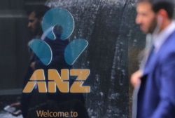 In this file photo, a pedestrian is reflected in the window of a branch of the Australia and New Zealand Banking Group (ANZ) in central Sydney, Australia, October 25, 2017.