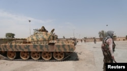 Un combattant kurde tient son arme près d'un char dans le quartier de Ghwairan à Hasaka, en Syrie, le 22 août 2016.