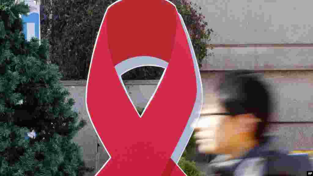 La silouhette d'un homme qui passe près du ruban rouge, symbole international de sensibilisation au sida à Séoul, Corée du Sud, 1er décembre 2015. 