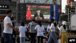 北京街頭的行人觀看電子屏幕上中國國家主席習近平。 （2020年5月18日）