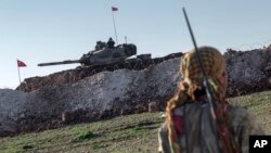 Un membre de la milice kurde syrienne des patrouilles des YPG près d'un char de l'armée turque à Esme, dans la province d'Alep, Syrie, le 22 février 2015.