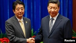 លោក Shinzo Abe នាយក​រដ្ឋ​មន្ត្រី​ជប៉ុន (ឆ្វេង) និង​លោក​ Xi Jinping ប្រធានា​ធិប​តី​ចិន (ស្តាំ) ចាប់​រលាក់ដៃ​គ្នា​​ក្នុង​ពេលជួបគ្នាក្នុង​កិច្ច​ប្រជុំ​ APEC នៅ​ទីក្រុង​ប៉េកាំងនៅថ្ងៃទី ១០ ខែវិច្ឆិកា ឆ្នាំ២០១៤។