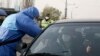 Фото: поліцейський в захисному костюмі заміряє температуру подорожуючому на в‘їзді до Києва, 16 квітня 2020 року