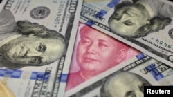 FILE: A U.S. 100 dollar bill featuring Benjamin Franklin is shown with a Chinese 100 yuan banknote with the late Chinese Chairman Mao Zedong, Jan. 21, 2016.