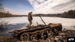 Фото березня 2022 року: Український військових поряд з російським танком в місті Тростянець 