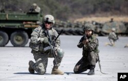 FILE - A U.S. Army soldier and a South Korean Army soldier take their position during joint military exercises between South Korea and the United States in Pocheon, north of Seoul, South Korea, March 25, 2015. China has proposed that the United States suspend joint military exercises with South Korea in exchange for North Korea putting on hold further nuclear and ballistic missile tests.