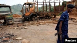 Un policier congolais assure la sécurité près des épaves de camions vandalisés au siège de mouvement politico-religieux Bundu Dia Kongo, à Matadi, Kongo central, 19 mars 2008. 