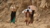 FILE - Yemenis carry relief supplies as they walk along a path outside the city of Taiz, Yemen, Jan. 17, 2016.