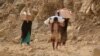 FILE - Yemenis carry relief supplies as they walk along a path outside the city of Taiz, Yemen, Jan. 17, 2016.