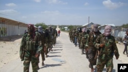 Des membres du groupe d'activistes somaliens d'Al-Shabab patrouillent à pied dans la banlieue de Mogadiscio, en Somalie, le 5 mars 2012.