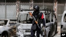 Un officier de police monte la garde à côté des voitures brûlées près du Splendid Hotel à Ouagadougou, Burkina Faso, 17 janvier 2016