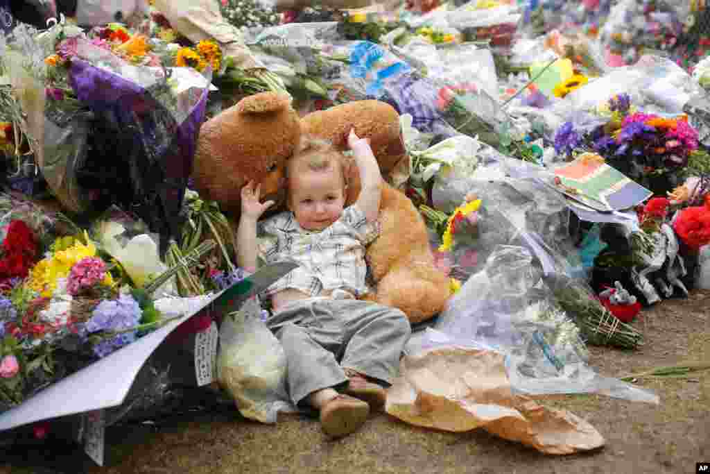 Nearly two old boy Kiran rests on a teddy bear in the flowers laying in front of the house of Nelson Mandela in Johannesburg, Dec. 9, 2013.