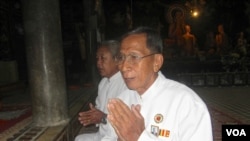 លោក​អាចារ្យ​យឹម​ វន បាន​ក្រោក​ពី​ព្រលឹម​មក​សូត្រ​យង្កិញ​នៅ​វត្ត​នន្ទមន្នី ដោយ​ភ្ជាប់​មក​ជា​មួយរូប​ព្រះ​ឆាយាល័ក្ស​ព្រះ​បាទ​សីហនុ​នៅ​លើ​អាវ​គាត់។ (ឃួន ធារ៉ា)