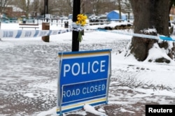 Flowers are left at the cordon near the tent covering the park bench where former Russian intelligence officer Sergei Skripal and his daughter Yulia were found poisoned, in Salisbury, Britain, March 19, 2018.