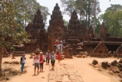 In this April 15, 2016, photo, tourists visit the Banteay Srey temple of the Angkor complex. The Angkor Wat temple is now off-limits to cars as authorities seek to ease traffic jams at the site that draws millions of tourists a year.