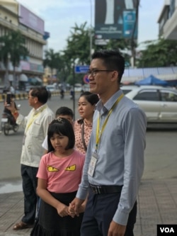 លោកយាង សុធារិន្ទ អតីតអ្នកយកព័ត៌មានឲ្យវិទ្យុអាស៊ីសេរី កាន់ដៃកូនស្រីរបស់លោក នៅមុខតុលាការដំបូងរាជធានីភ្នំពេញ កាលពីថ្ងៃសុក្រ ទី៣០ ខែសីហា ឆ្នាំ២០១៩។ (អូន ឆេងប៉រ/VOA)