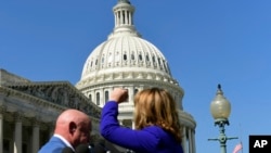 La exlegisladora demócrata por Arizona Gabrielle Giffords acompañada de su esposo el astronauta Mark Kelly levanta el puño hacia el Congreso de EE.UU. mientras pide un control de armas más estricto luego del ataque masivo en un concierto en Las Vegas, Nevada. Oct. 2, 2017.