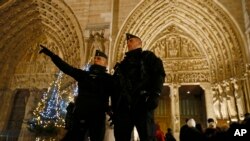POlisi wa Ufaransa wakisimama karibu na mlango wa kuingia kanisa la Notre Dame Cathedral wakati waumini wanawasili kwa Misa ya Krismas.