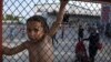 A child stands behind a fence during a protest against the living conditions at the Oreokastro camp, near the northern town of Thessaloniki, Greece, June 25, 2016.