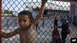 A child stands behind a fence during a protest against the living conditions at the Oreokastro camp, near the northern town of Thessaloniki, Greece, June 25, 2016.