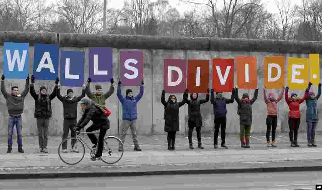 Les manifestants de l'organisation environnementale 'Greenpeace' affichent des pancartes montrant une partie d'un slogan au Mémorial du Mur de Berlin à Berlin, en Allemagne, le vendredi 20 janvier 2017. Le slogan complet se lit comme suit: «M. Président, les murs se divisent, construisent des ponts! '. Le président élu américain Donald Trump sera inauguré plus tard dans la journée.