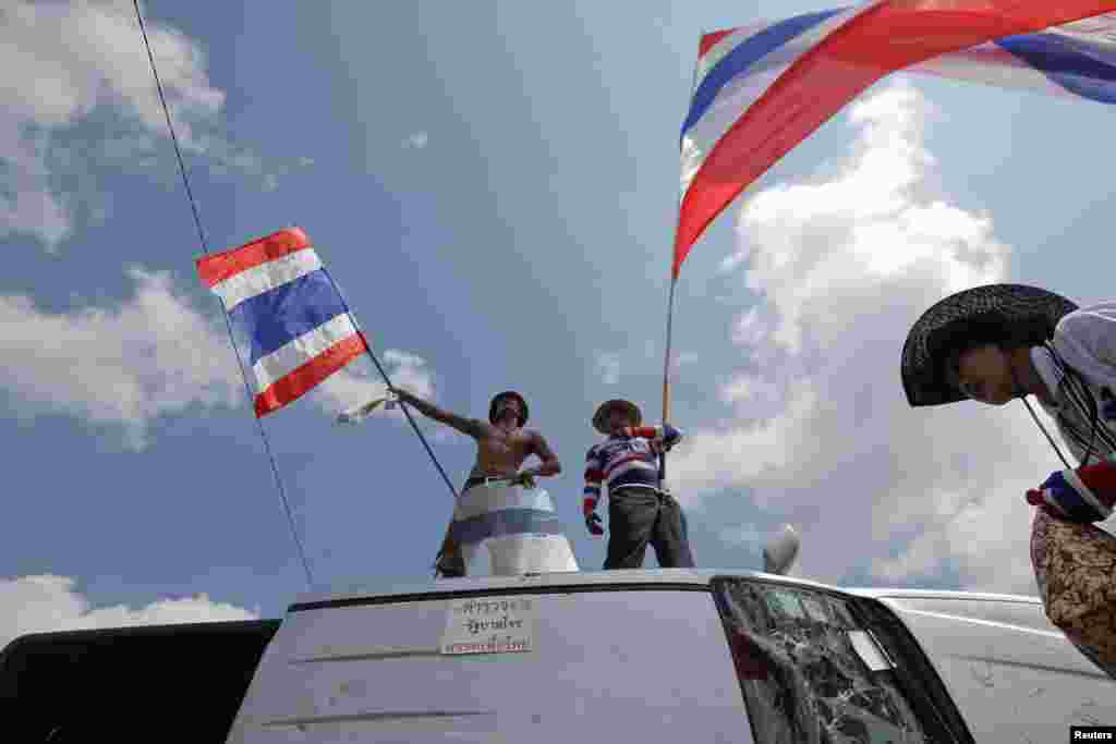 Anti-government protesters celebrate on top of a destroyed police vehicle after clashes near the Government House in Bangkok, Feb. 18, 2014.