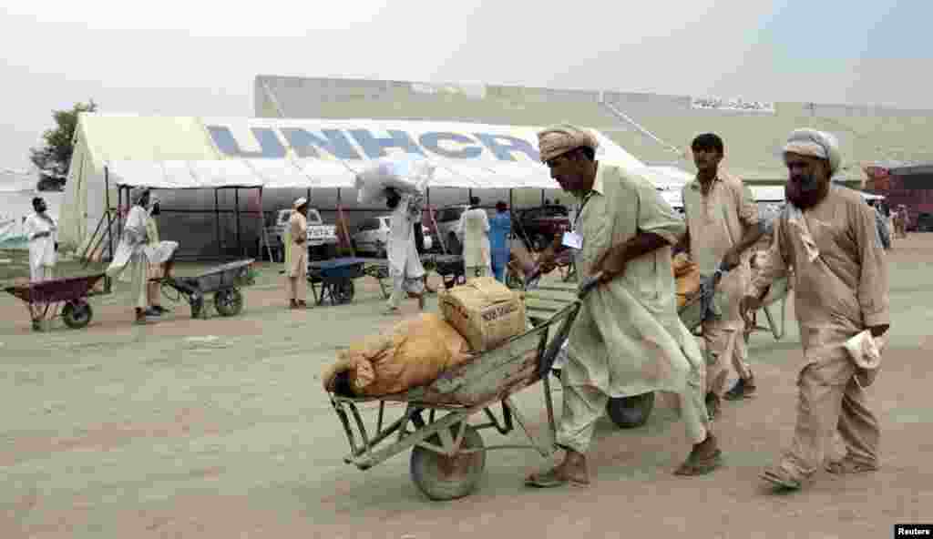 Un ouvrier pousse une brouette contenant l'aide pour les déplacés à l'intérieur d'un centre de distribution alimentaire dans un stade à Bannu, dans le nord-Pakistan, le 25 Juillet 2014.