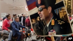 Un partisan du président Abdel-Fattah el-Sissi avec une affiche de campagne devant l'Autorité nationale des élections au Caire, Égypte, 29 janvier 2018.