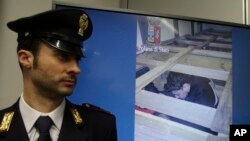 Un policier italien se tient devant un écran qui montre des migrants dans un camion, à Milan, Italie, le 30 janvier 2017.
