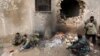 Rebel fighters rest near a hole in the wall by a fire on the outskirts of the northern Syrian town of al-Bab, Jan. 15, 2017. 
