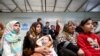 FILE - Syrian refugees wait to receive treatment at a health center, during the visit of Slovenian President Borut Pahor (back C) to the refugee camp Al-Zaatari in Jordan, near the border with Syria, Dec. 3, 2016.