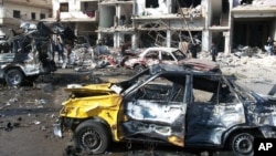Ciudadanos sirios observan el lugar donde dos bombas explotaron en el barrio progubernamental de Zahraa, en Homs, Siria, el domingo, 21 de febrero de 2016.