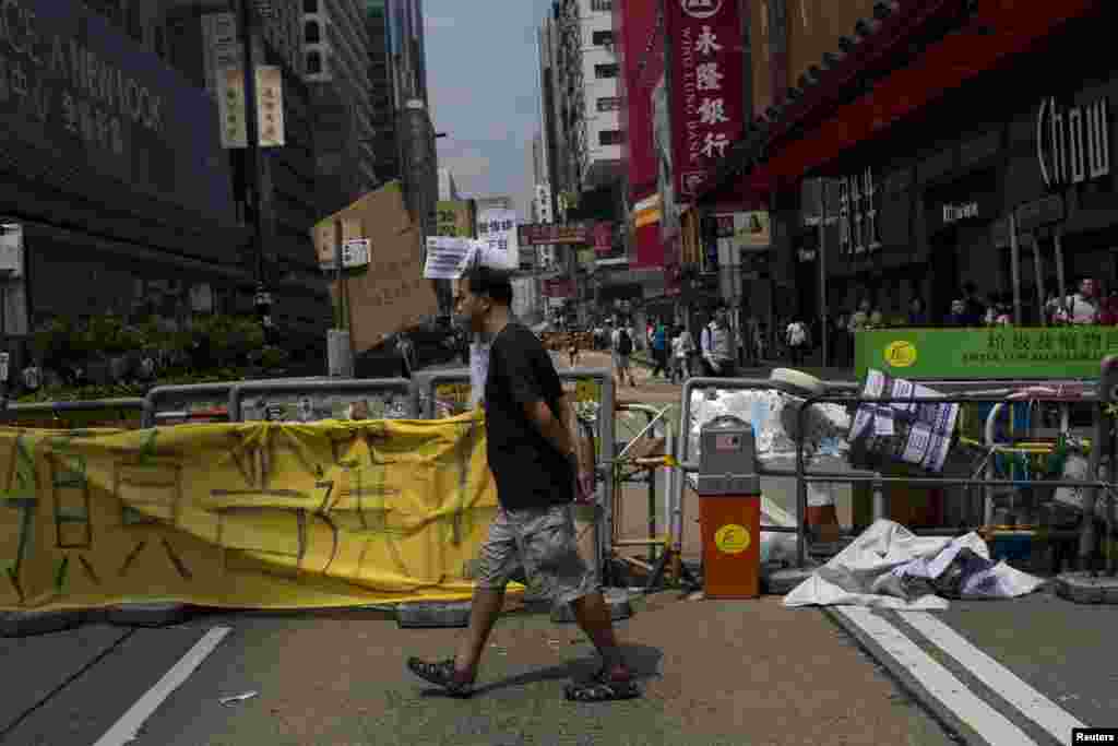 A man walks past a road block setup by protesters at a main street at Mongkok shopping district in Hong Kong, Sept. 30, 2014.